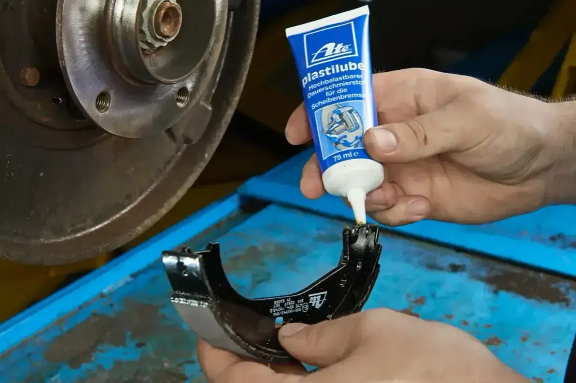 Mechanik aplikuje smar ATE Plastilube na szczękę hamulcową, dbając o prawidłowe działanie układu. Jaki smar do prowadnic hamulcowych? Ten jest idealny.