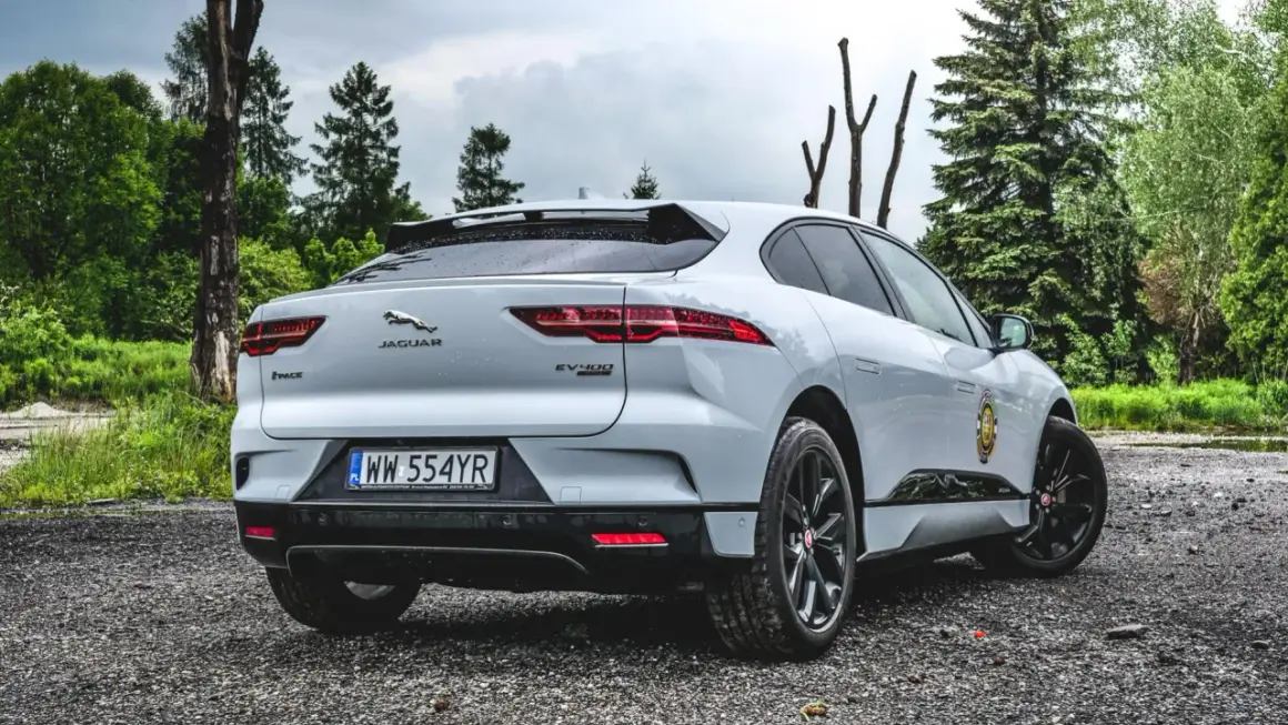 Biały Jaguar I-PACE EV400 na tle leśnej drogi.